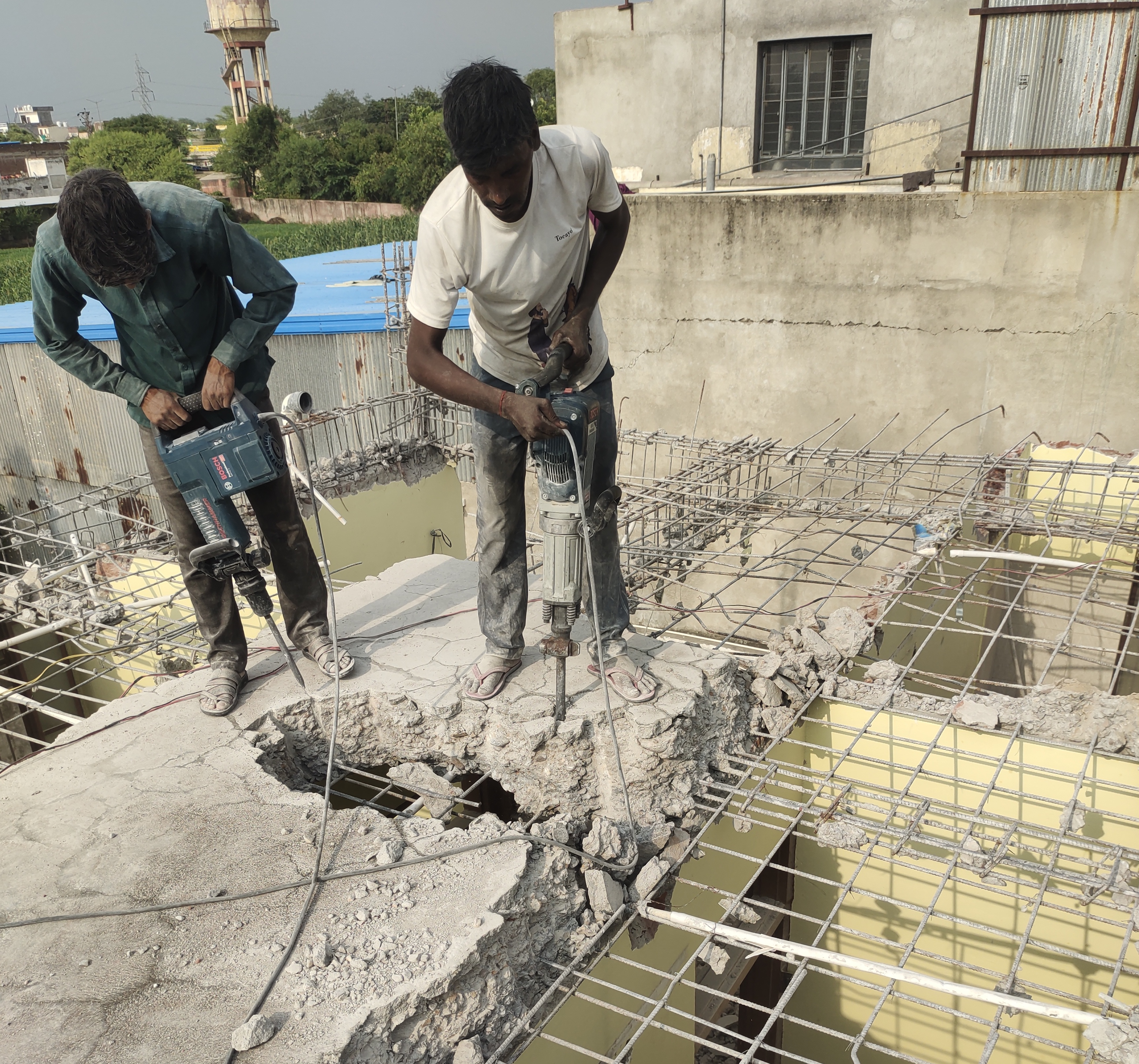 Professional construction workers operating demolition hammers on slab
